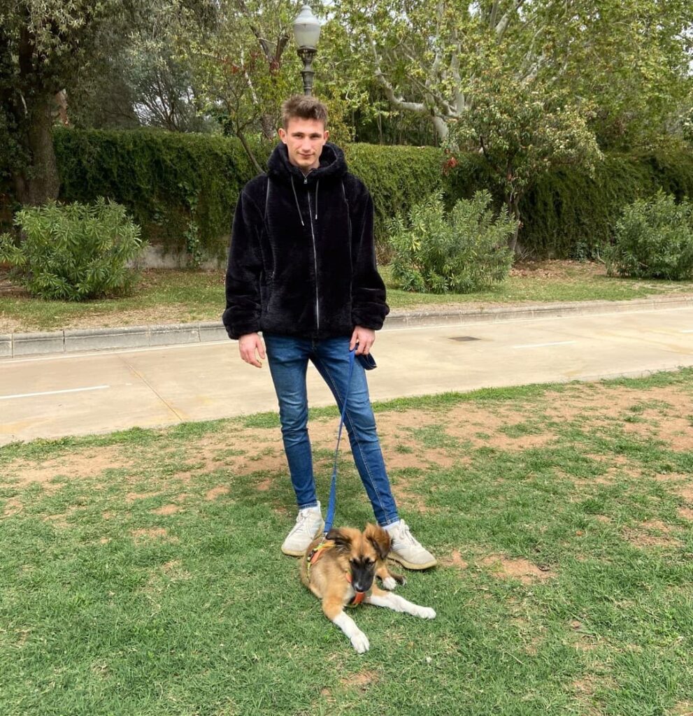 Dimanimales  con sudadera negra cogiendo la correa de un cachorro de seis meses que le han dado la oportunidad de cuidar como paseador de perros 