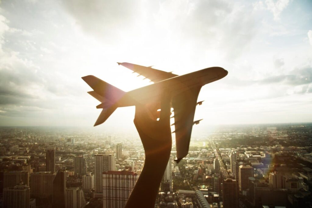 juguete de avión volando por la ciudad cogido por una mano